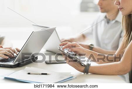 Business people using technology in office meeting View Large Photo Image Picture - Business people using technology in office meeting. Fotosearch