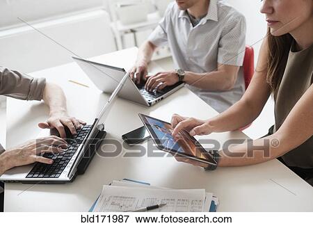 Business people using technology in office meeting View Large Photo Image Stock Photo - Business people using technology in office meeting. Fotosearch