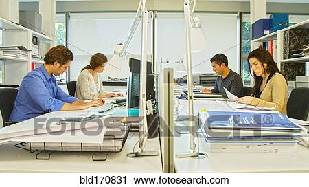 Stock Image - Business people working at desk in office. Fotosearch