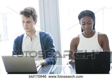 Stock Photograph - Business people working on laptops in office. Fotosearch