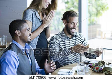 Stock Photograph - Businessman opening gifts at birthday lunch. Fotosearch