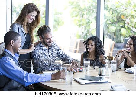 Stock Photography - Businessman opening gifts at birthday lunch. Fotosearch