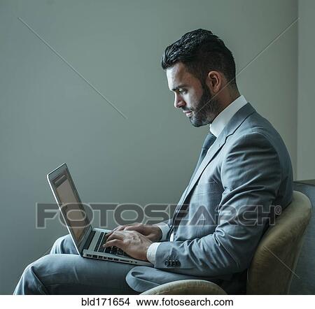 Picture - Businessman using laptop in armchair. Fotosearch