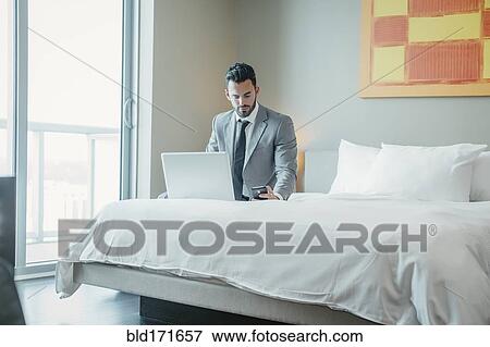 Businessman using laptop on hotel bed View Large Photo Image Stock Photo - Businessman using laptop on hotel bed. Fotosearch