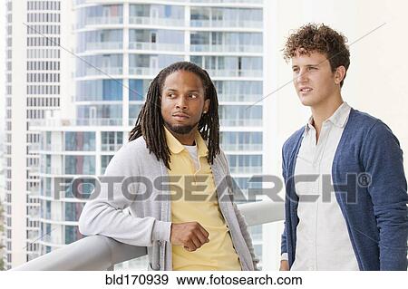 Stock Photo - Businessmen standing on urban balcony. Fotosearch