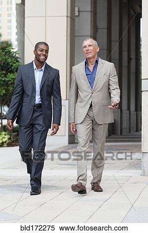 Stock Photography - Businessmen talking on city sidewalk. Fotosearch