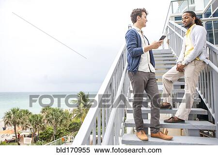 Stock Photography - Businessmen talking on steps over urban beach. Fotosearch