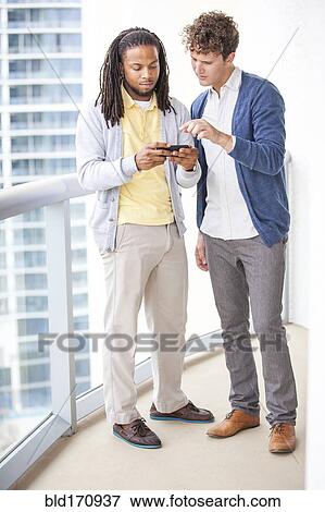 Businessmen using cell phone on urban balcony View Large Photo Image Stock Photo - Businessmen using cell phone on urban balcony. Fotosearch