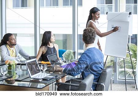 Businesswoman giving presentation in office meeting View Large Photo Image Stock Photo - Businesswoman giving presentation in office meeting. Fotosearch