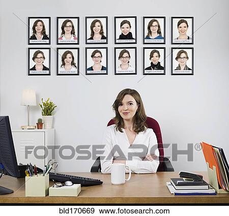 Stock Photo - Businesswoman smiling under award pictures in office. Fotosearch