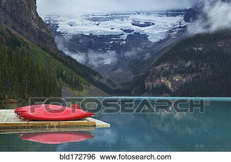 Stock Photograph - Canoes on wooden dock over still remote lake. Fotosearch