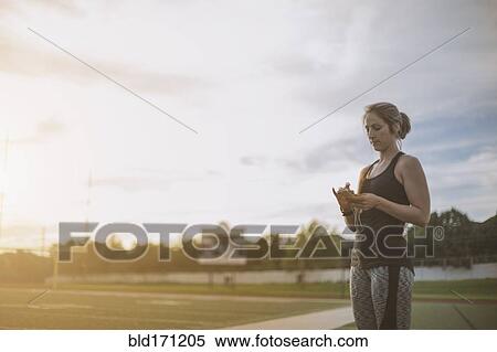 Stock Photography - Caucasian athlete listening to mp3 player on sports field. Fotosearch