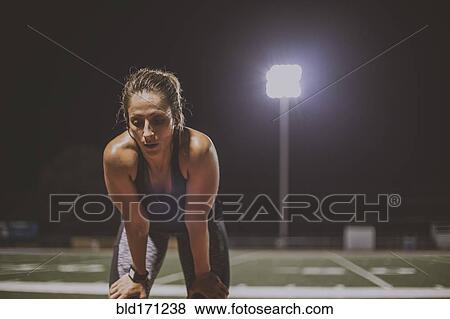 Stock Photo - Caucasian athlete resting on sports field. Fotosearch