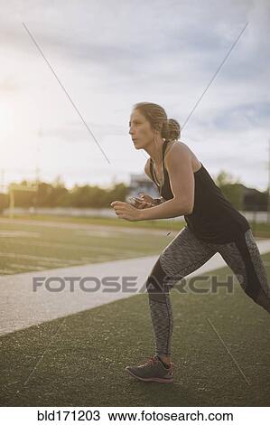 Stock Image - Caucasian athlete stretching on sports field. Fotosearch