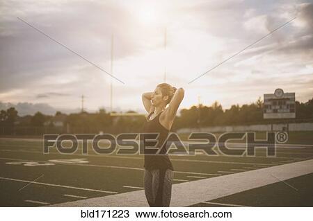 Stock Image - Caucasian athlete tying her hair up on sports field. Fotosearch