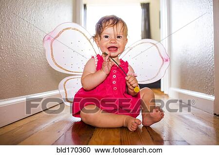 Stock Image - Caucasian baby girl playing in fairy wings. Fotosearch
