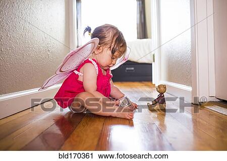 Stock Image - Caucasian baby girl playing in fairy wings. Fotosearch