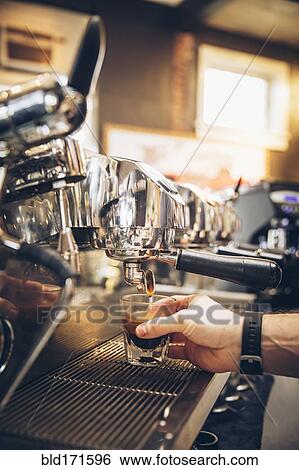 Stock Photograph - Caucasian barista pouring espresso shot in cafe. Fotosearch