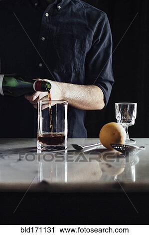 Stock Image - Caucasian bartender pouring cocktail in glass. Fotosearch