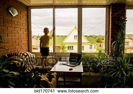Caucasian boy looking out living room window View Large Photo Image Stock Image - Caucasian boy looking out living room window. Fotosearch