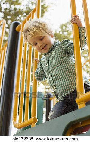 Stock Photography - Caucasian boy on play structure in playground. Fotosearch
