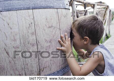 Stock Photo - Caucasian boy peering into barrel. Fotosearch