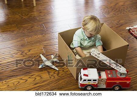 Picture - Caucasian boy playing in cardboard box. Fotosearch