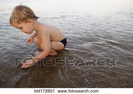 Caucasian boy playing in water on beach View Large Photo Image Stock Image - Caucasian boy playing in water on beach. Fotosearch
