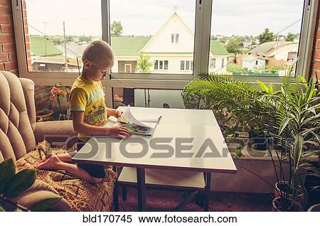 Stock Photography - Caucasian boy reading magazine at desk. Fotosearch