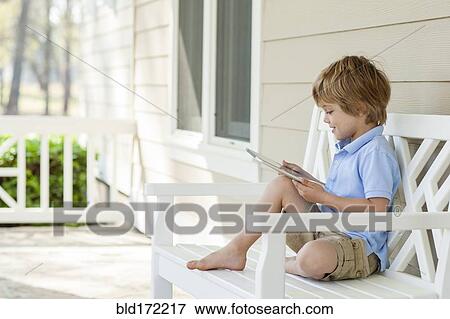 Stock Photo - Caucasian boy using digital tablet on patio. Fotosearch