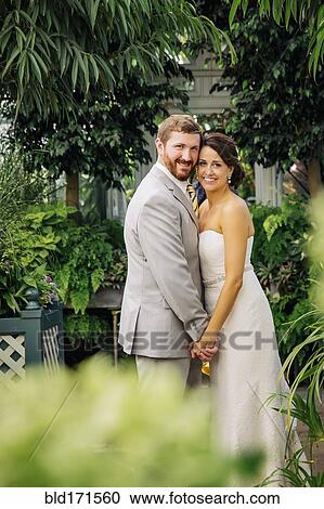 Stock Image - Caucasian bride and groom hugging in garden. Fotosearch