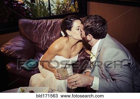 Stock Image - Caucasian bride and groom kissing in living room. Fotosearch