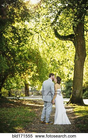 Stock Photography - Caucasian bride and groom kissing on dirt path. Fotosearch