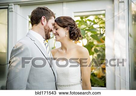 Caucasian bride and groom touching foreheads in garden View Large Photo Image Stock Image - Caucasian bride and groom touching foreheads in garden. Fotosearch