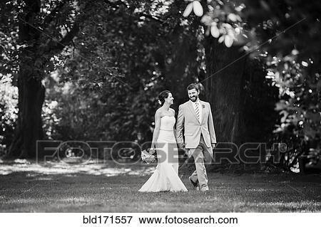Caucasian bride and groom walking in grass View Large Photo Image Stock Photo - Caucasian bride and groom walking in grass. Fotosearch