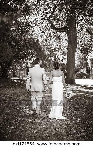 Picture - Caucasian bride and groom walking on dirt path. Fotosearch