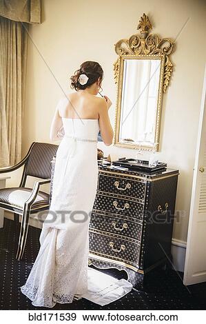 Stock Photo - Caucasian bride applying makeup in mirror. Fotosearch