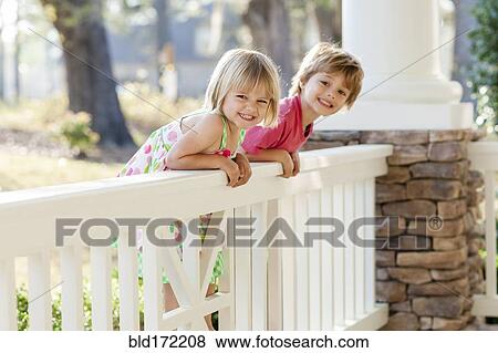 Stock Photo - Caucasian brother and sister leaning over porch. Fotosearch