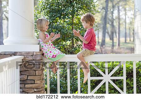 Stock Image - Caucasian brother and sister playing on patio. Fotosearch