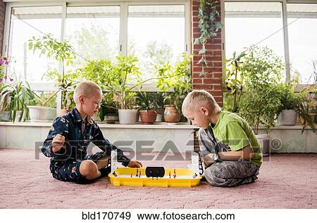 Stock Photo - Caucasian brothers playing game on floor. Fotosearch