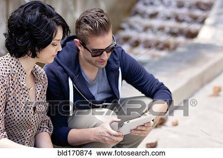 Picture - Caucasian business people using digital tablet by fountain. Fotosearch