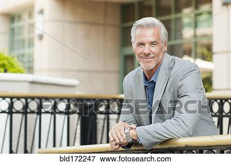 Stock Photo - Caucasian businessman leaning over banister. Fotosearch
