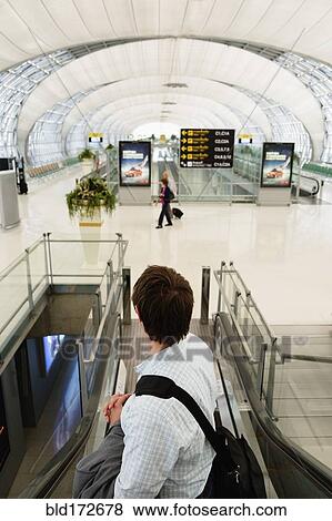 Stock Photo - Caucasian businessman on escalator in airport. Fotosearch
