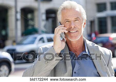 Caucasian businessman talking on cell phone in city View Large Photo Image Picture - Caucasian businessman talking on cell phone in city. Fotosearch