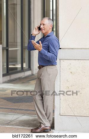 Caucasian businessman talking on cell phone on city sidewalk View Large Photo Image Stock Image - Caucasian businessman talking on cell phone on city sidewalk. Fotosearch