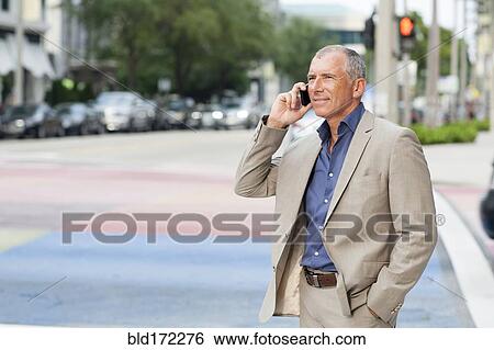 Caucasian businessman talking on cell phone at crosswalk View Large Photo Image Stock Photograph - Caucasian businessman talking on cell phone at crosswalk. Fotosearch