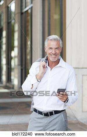 Stock Image - Caucasian businessman using cell phone in city. Fotosearch