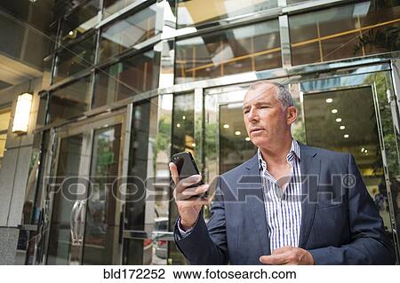 Caucasian businessman using cell phone outside office View Large Photo Image Stock Image - Caucasian businessman using cell phone outside office. Fotosearch