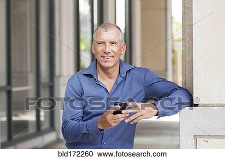 Stock Image - Caucasian businessman using cell phone in city. Fotosearch