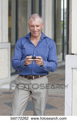 Caucasian businessman using cell phone on city sidewalk View Large Photo Image Stock Image - Caucasian businessman using cell phone on city sidewalk. Fotosearch